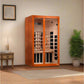 Orange framed two-person infrared sauna with glass doors and light wood interior, shown in room setting with decorative plant