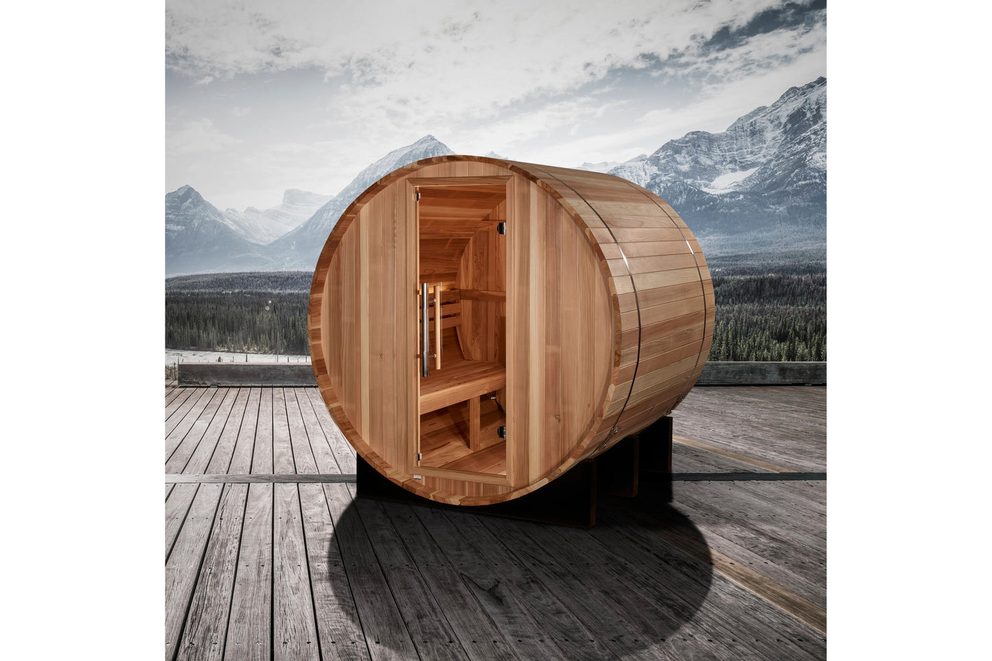 Cedar wood barrel sauna with open door showing interior benches, positioned on wooden deck with snow-capped mountains in back