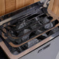 Black sauna heater with gray sauna stones in multiple compartments, lid open, on wooden wall background