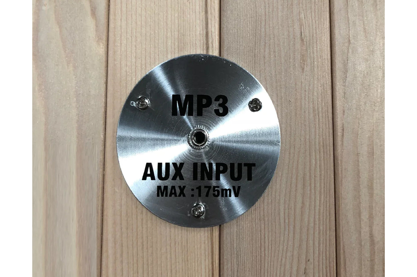 Polished stainless steel circular control panel with MP3 and AUX INPUT MAX 175mV text, mounted on wood background
