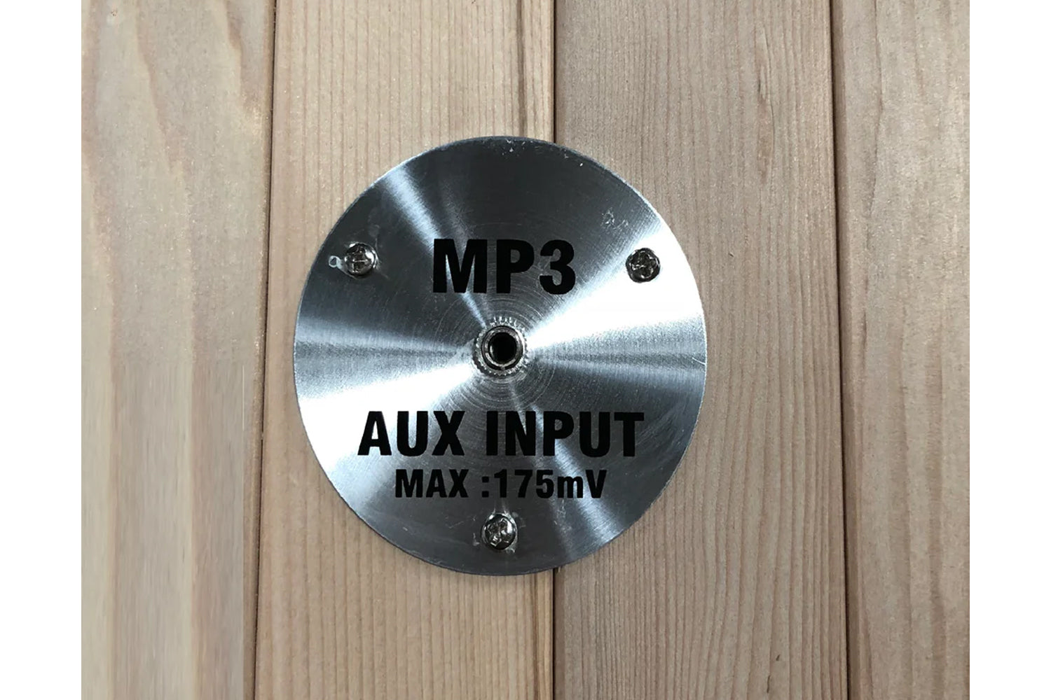 Polished stainless steel circular control panel with MP3 and AUX INPUT MAX 175mV text, mounted on wood background
