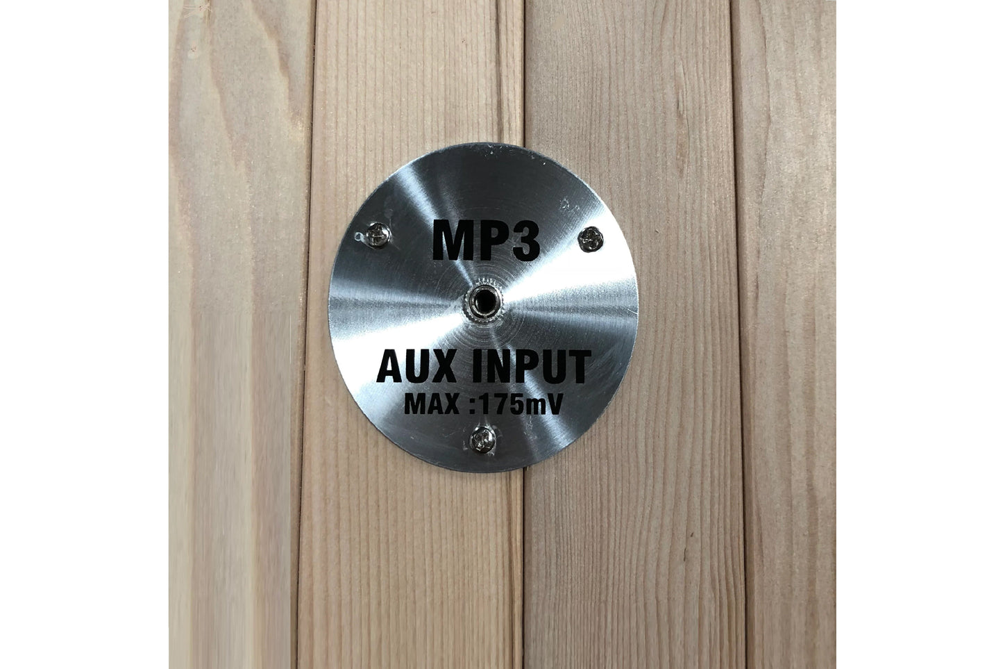 Silver circular metal plate with MP3 and AUX INPUT MAX:175mV text, mounted on light wood background