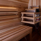 Cedar sauna interior with tiered wooden benches, wall-mounted shelving with Harvia heater, and wooden ceiling beams