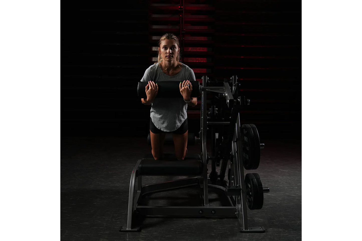 Woman wearing gray t-shirt using Hammer Strength assisted leg press machine in gym setting