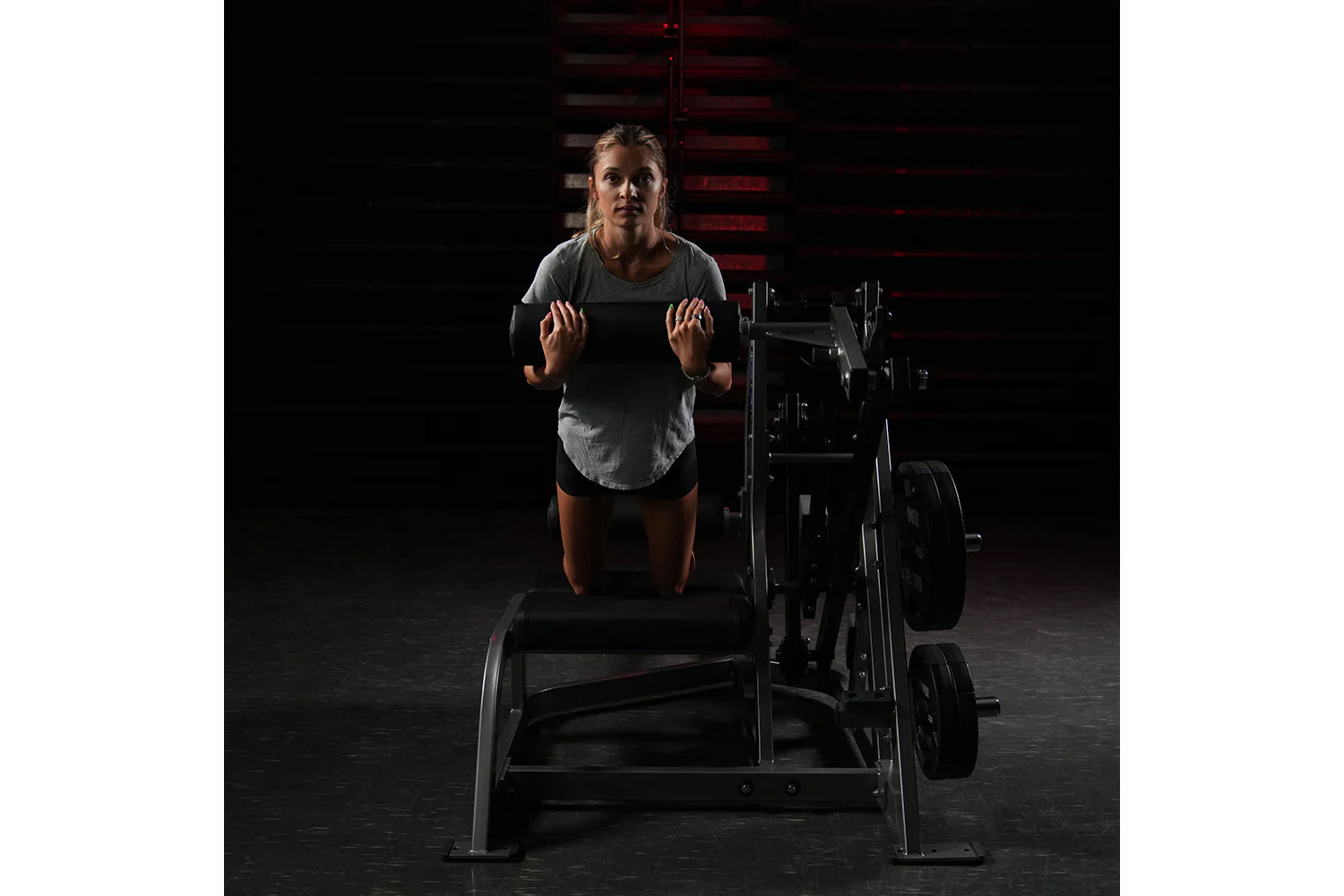 Woman wearing gray t-shirt using Hammer Strength assisted leg press machine in gym setting