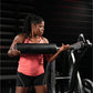 Woman wearing coral halter tank top and black shorts using Hammer Strength assisted leg press machine in gym setting