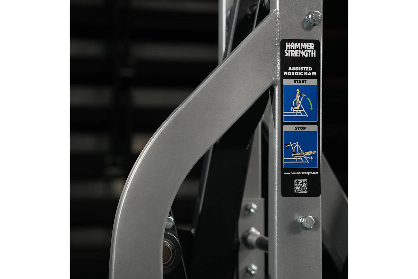 Hammer Strength Assisted Nordic Ham exercise machine with instructional label showing start and stop positions on metal frame