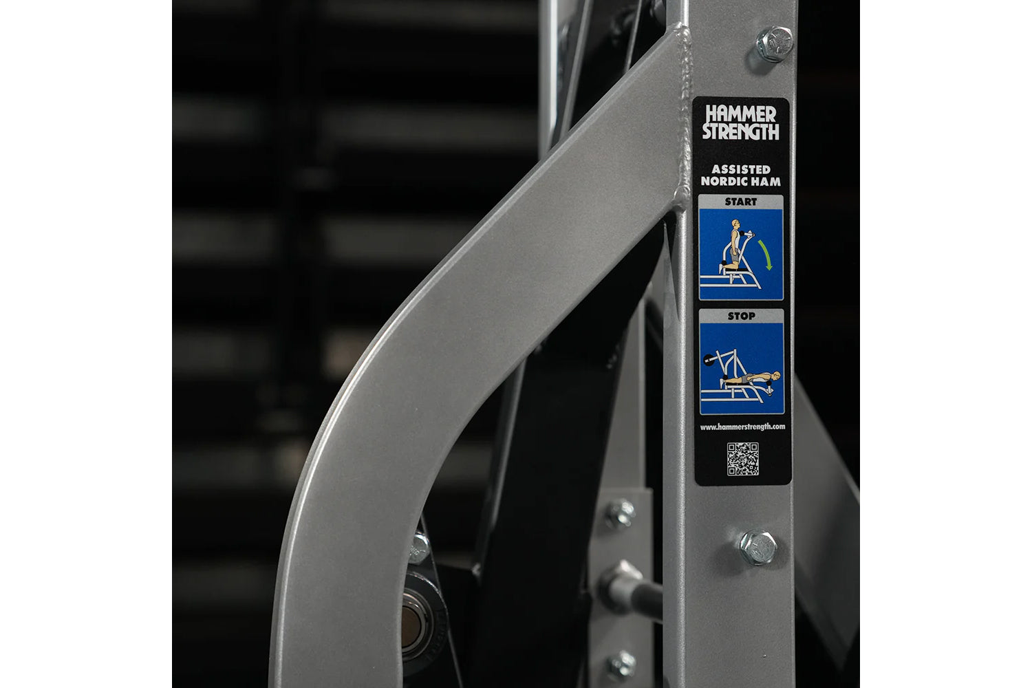Hammer Strength Assisted Nordic Ham exercise machine with instructional label showing start and stop positions on metal frame