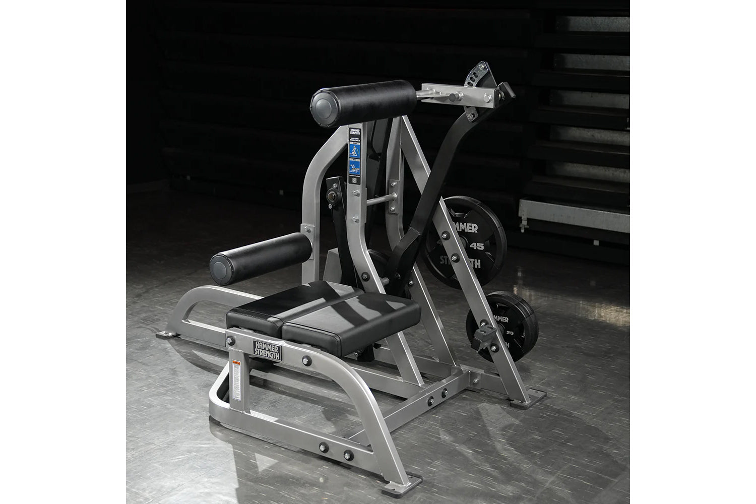 Hammer Strength assisted Nordic ham machine with gray frame, black padded seat, weight plates, and dual handles on concrete f