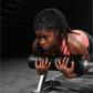 Woman in coral and black sports tank top performing barbell exercise on gym equipment against dark background