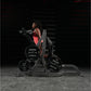 Woman in red tank top using Hammer Strength assisted Nordic hamstring machine with weight plates in dark gym setting