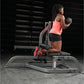 Woman wearing coral tank top and black shorts holding dumbbells on Hammer Strength exercise machine in gym setting