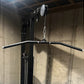 Black and silver dual pulldown/row machine with curved bar attachment and chain system, mounted on concrete wall