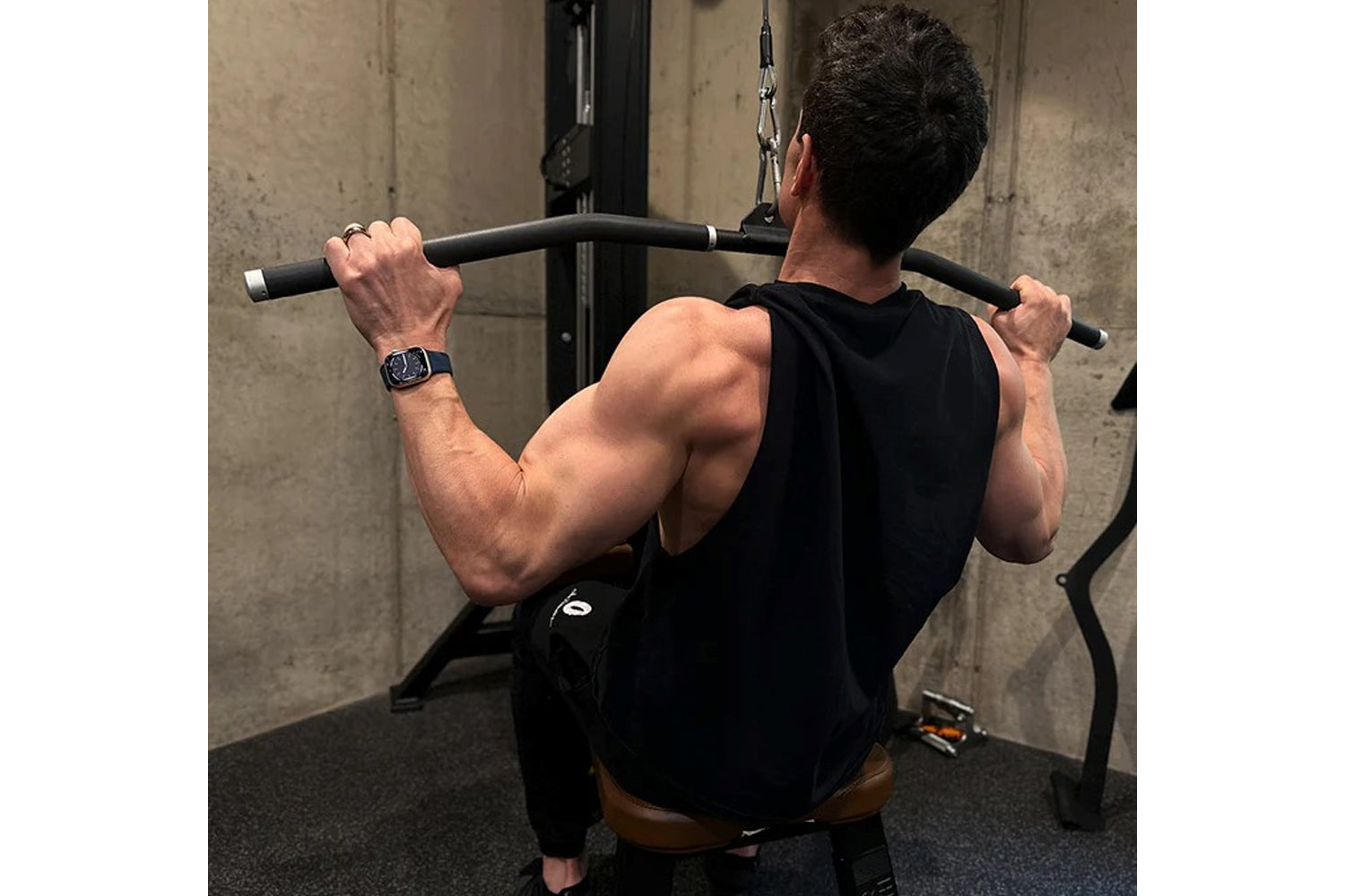 Man performing lat pulldown exercise on Hammer Strength dual pulldown/row machine in gym, wearing black sleeveless shirt