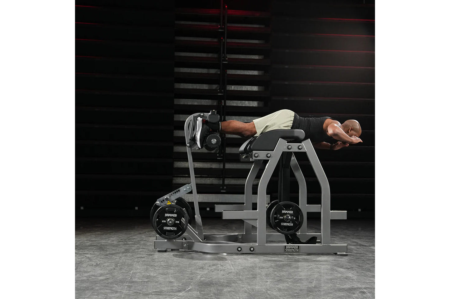 Man using gray and black Hammer Strength glute-ham reverse hyper combo bench machine with loaded weight plates in gym setting