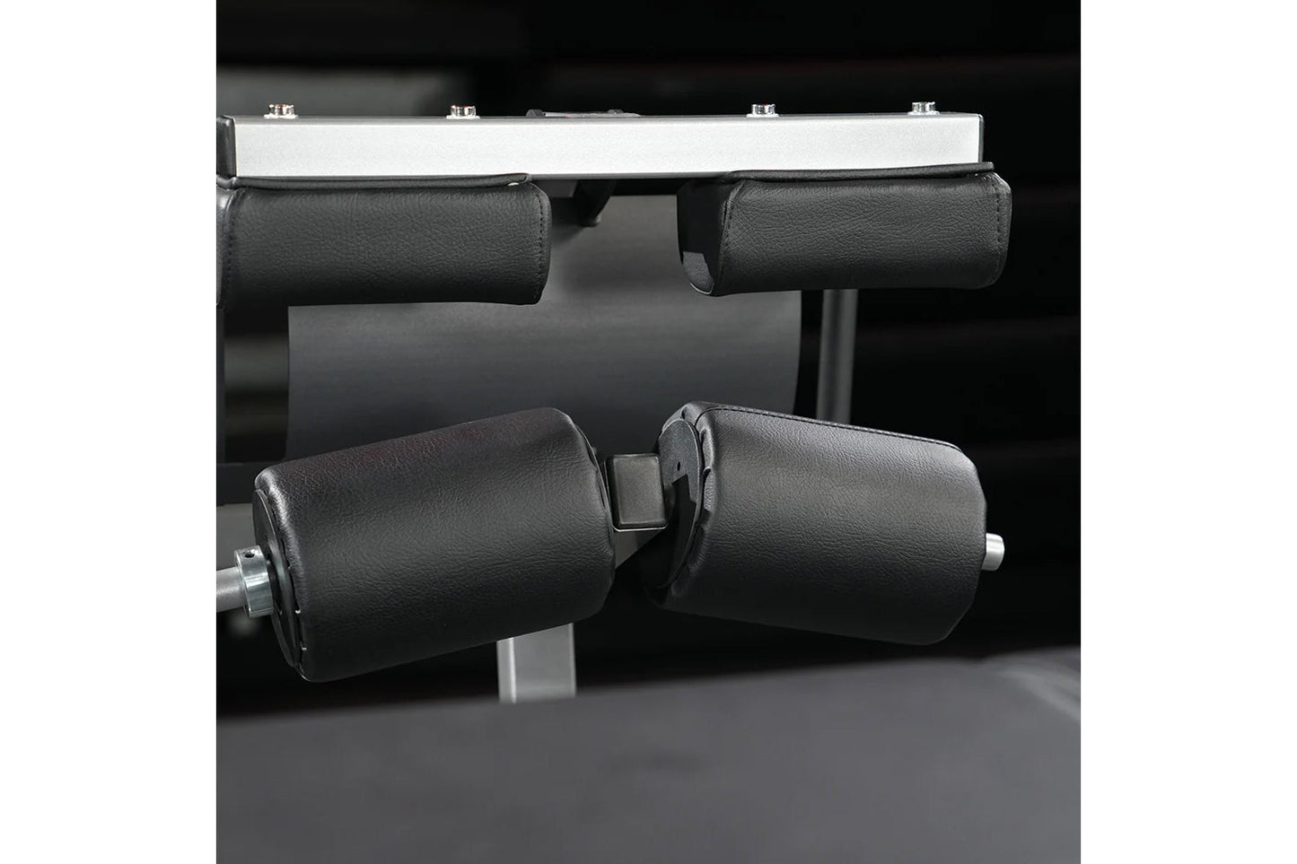 Hammer Strength Glute-Ham Reverse Hyper Combo Bench Machine with black padded leg rollers and silver frame on dark background