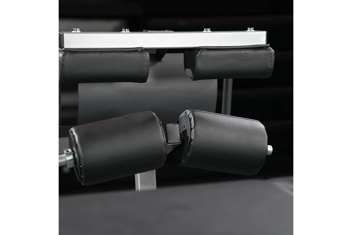 Hammer Strength Glute-Ham Reverse Hyper Combo Bench Machine with black padded leg rollers and silver frame on dark background