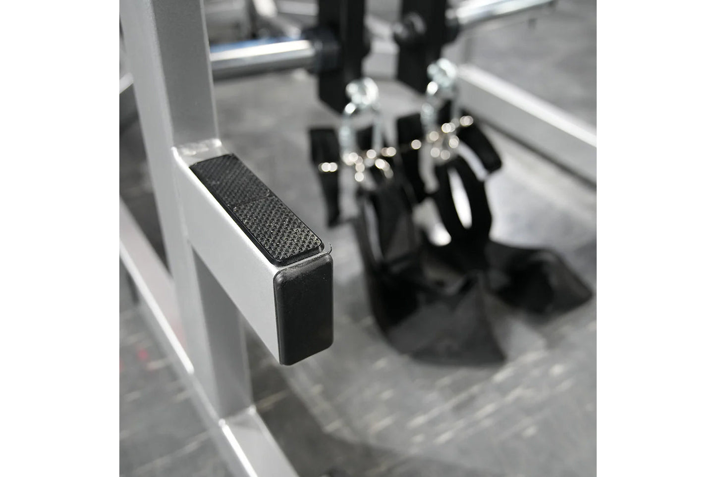 Black and gray metal exercise machine with textured foot platform and lever handles, close-up detail view