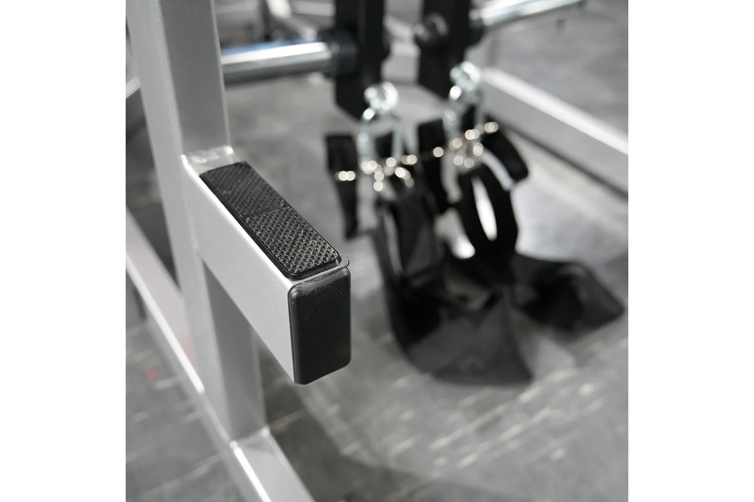 Black and gray metal exercise machine with textured foot platform and lever handles, close-up detail view