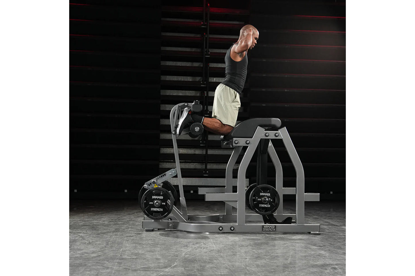 Man performing reverse hyper exercise on gray Hammer Strength machine with black weight plates in gym setting