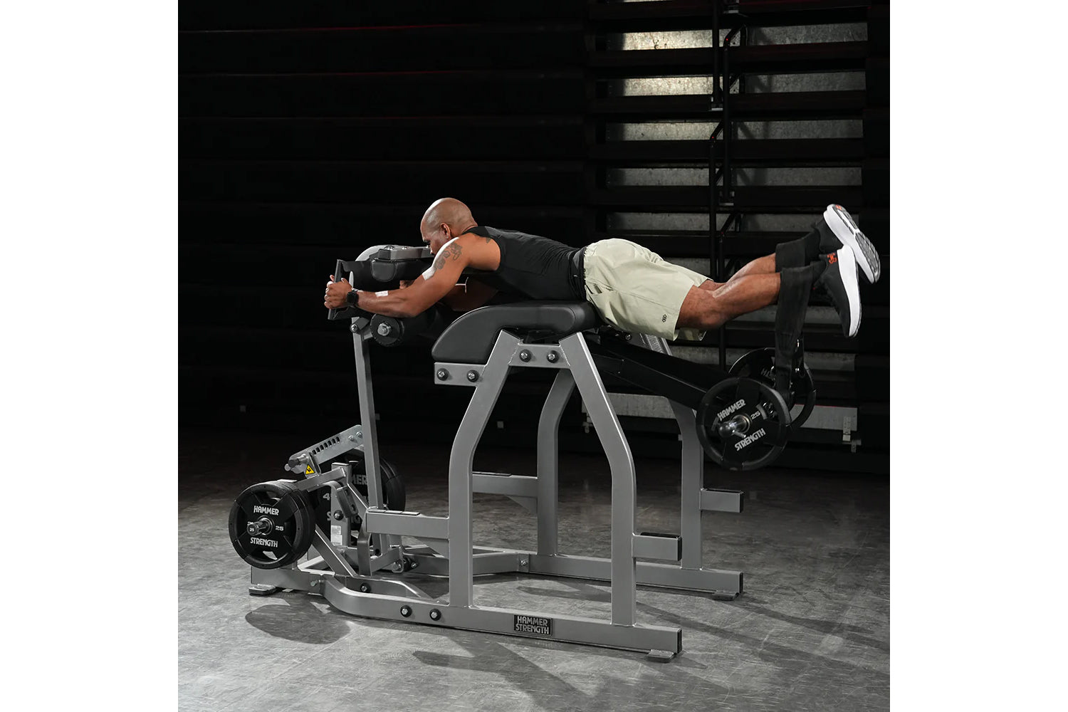 Man using gray and black Hammer Strength Glute-Ham Reverse Hyper Combo machine in gym setting, demonstrating exercise form