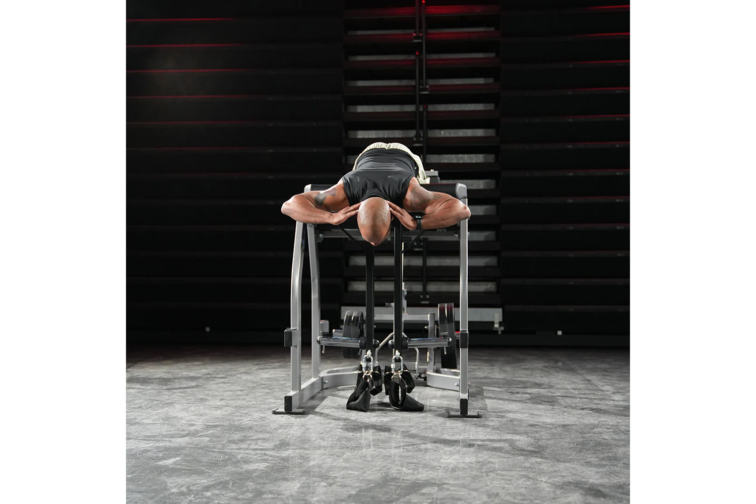 Athlete performing reverse hyper exercise on silver and black Hammer Strength gym machine in industrial warehouse setting