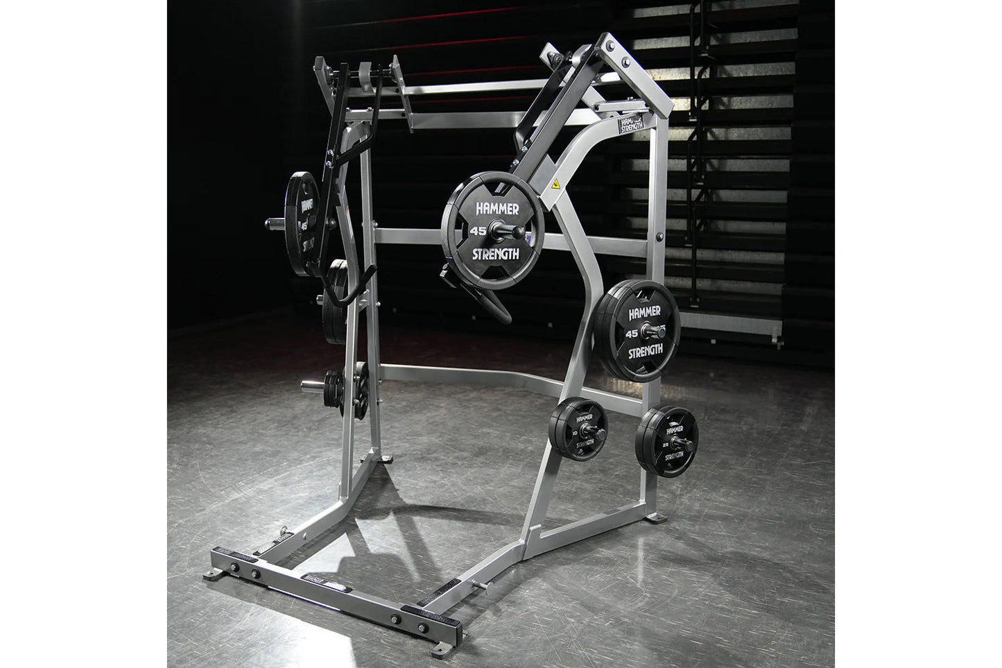 Hammer Strength Ground Base Jammer with white frame, black weight plates labeled 45 pounds, and storage pegs on gym floor