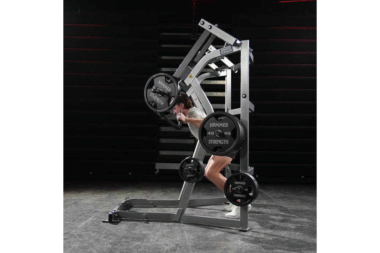 Man using Hammer Strength ground base jammer machine with weighted plates in gym setting
