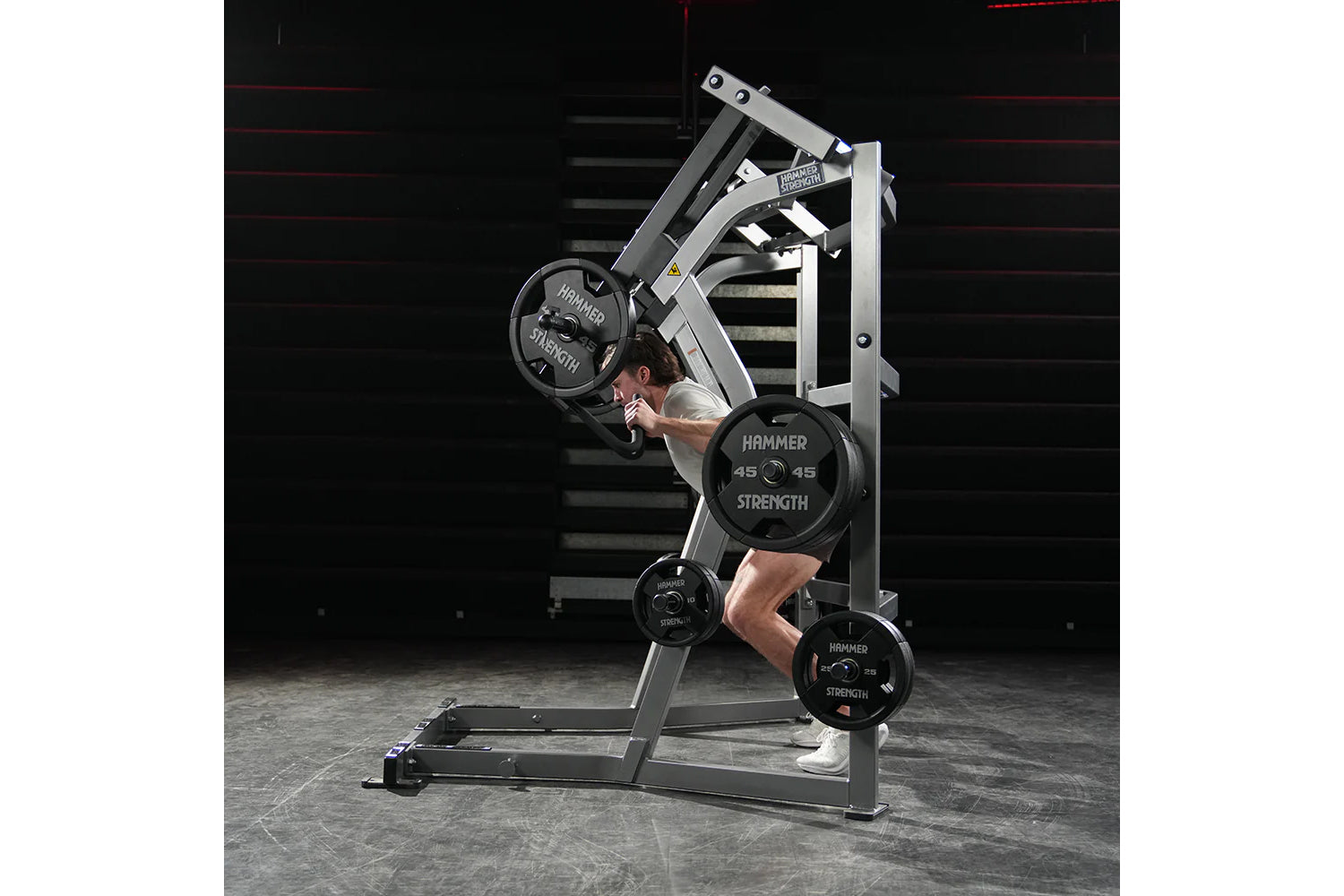 Man using Hammer Strength ground base jammer machine with weighted plates in gym setting