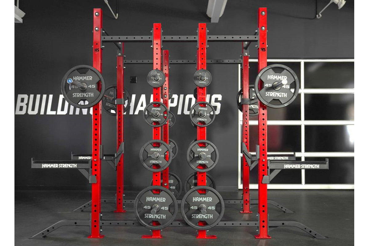 Hammer Strength red and gray half rack combo with weight plates loaded on pegs in gym setting