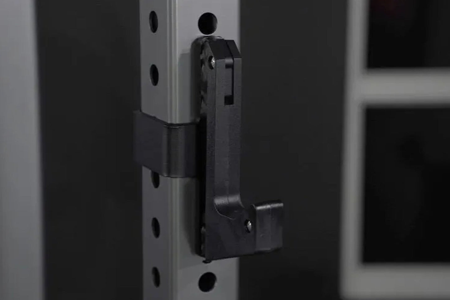 Black metal half rack attachment with lever arm and adjustment pins mounted on vertical post with holes