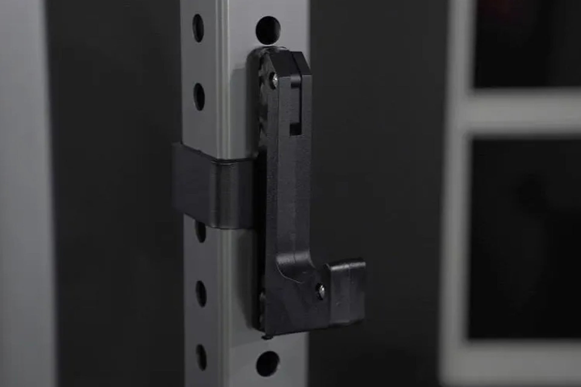 Black metal half rack attachment with lever arm and adjustment pins mounted on vertical post with holes