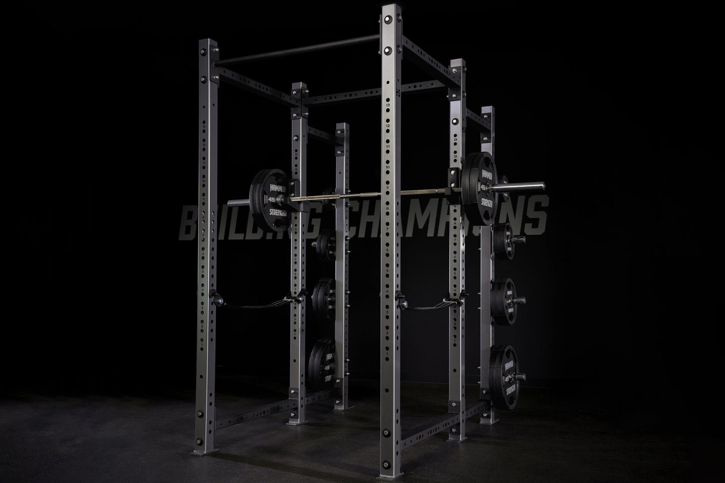 Black steel power rack with perforated uprights, multiple horizontal bars, loaded barbells on pegs, on dark background