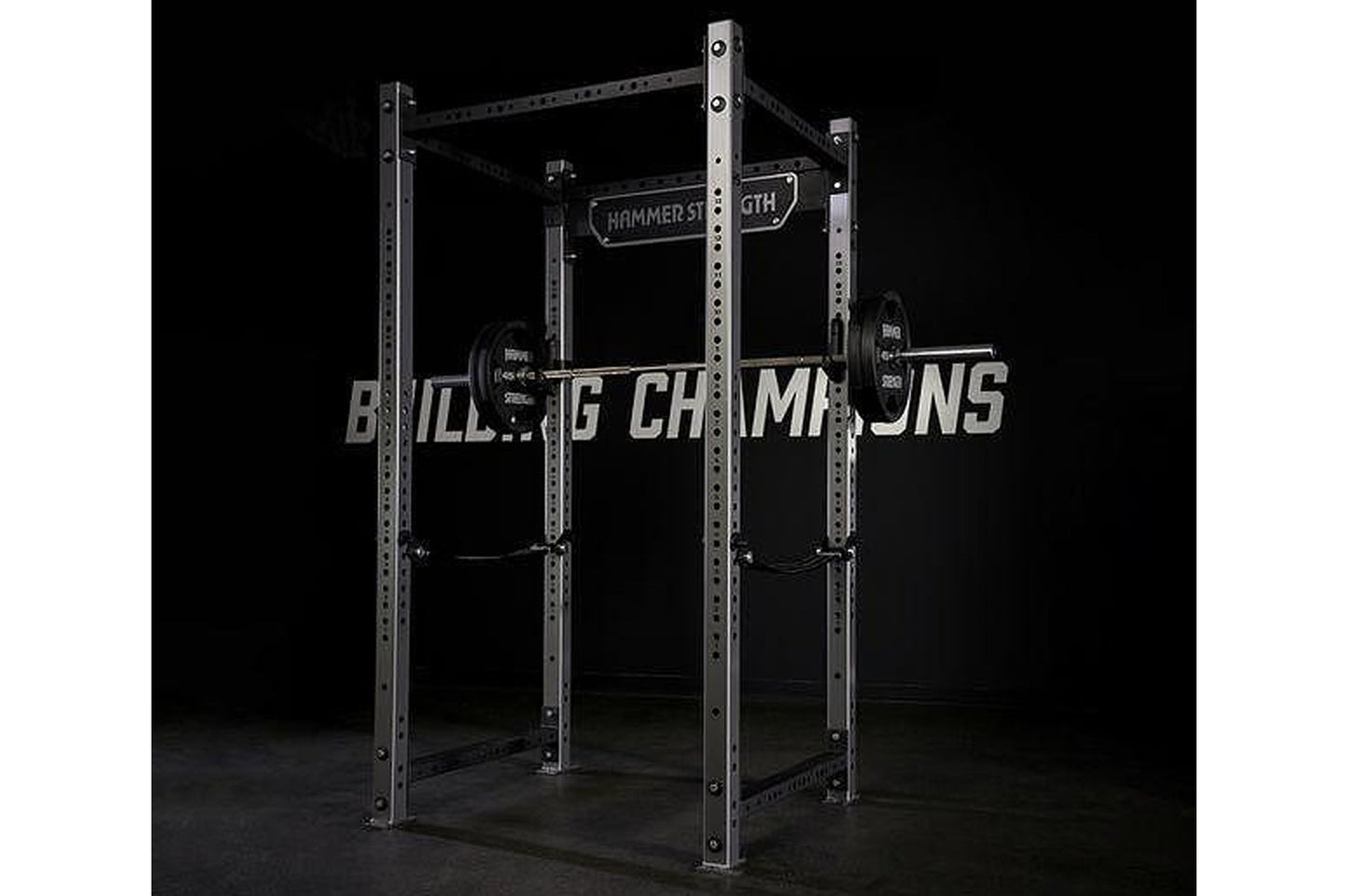 Hammer Strength HD athletic power rack with stainless steel frame, loaded barbell, and weight plates on black background