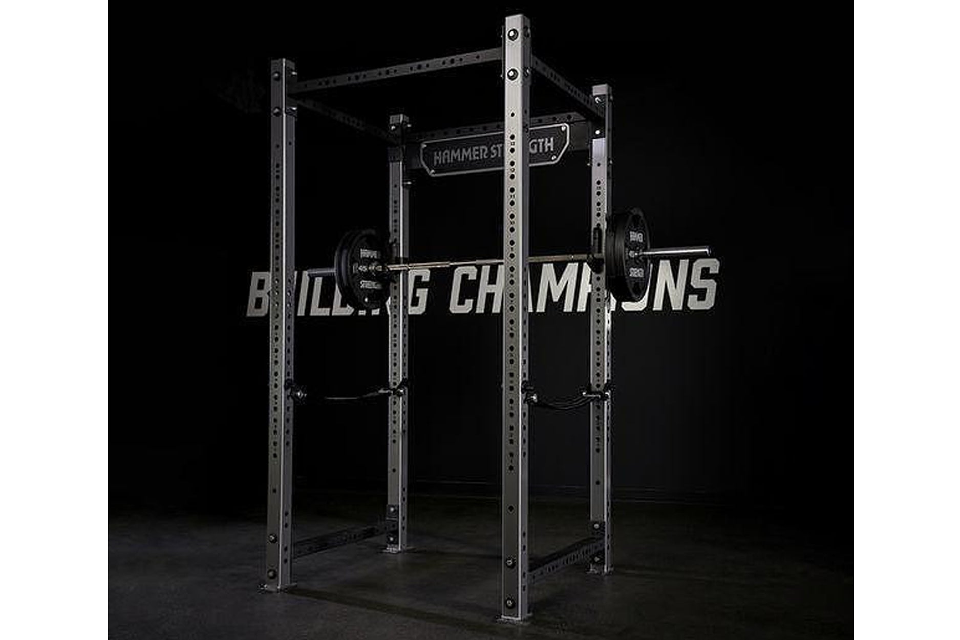 Hammer Strength HD athletic power rack with stainless steel frame, loaded barbell, and weight plates on black background