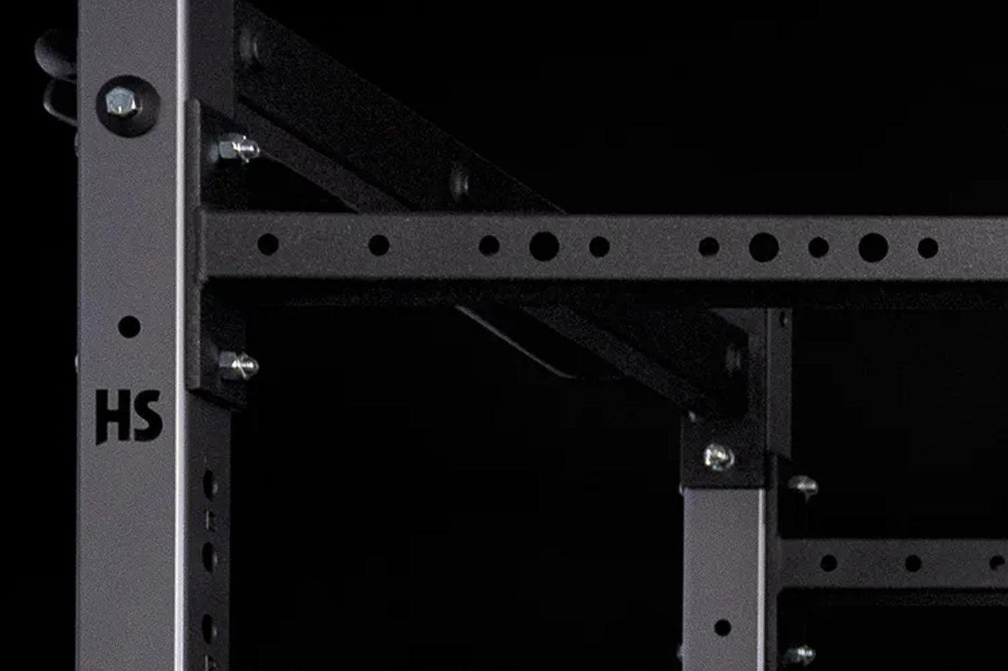 Black metal squat stand with perforated uprights, horizontal safety bars, and chrome bolts, shown on dark background