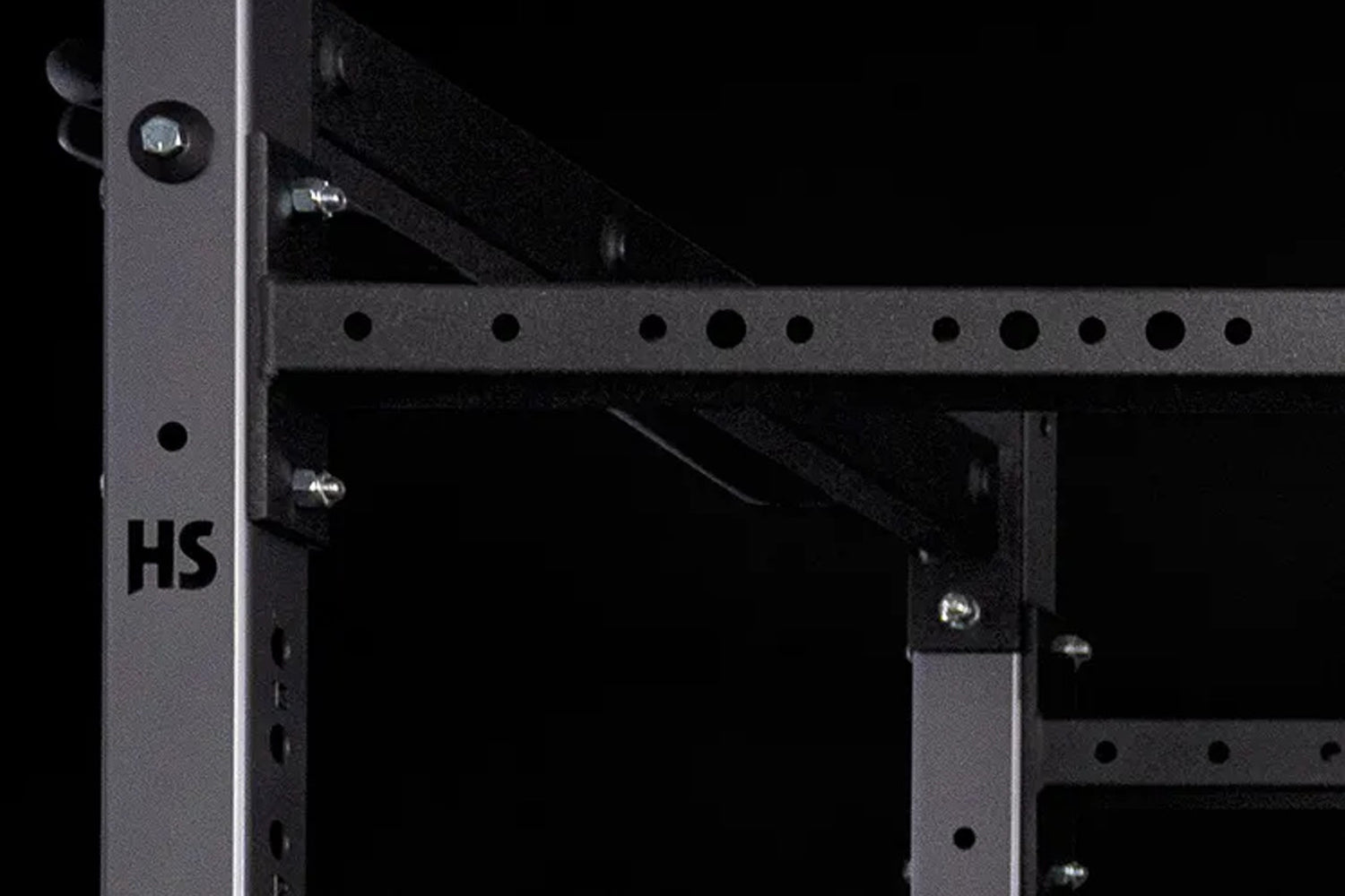 Black metal squat stand with perforated uprights, horizontal safety bars, and chrome bolts, shown on dark background