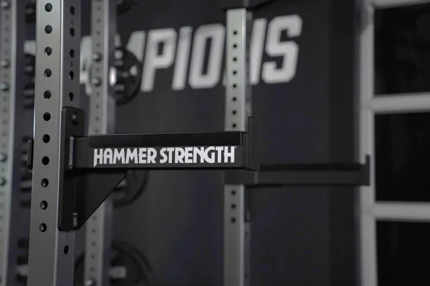 Black Hammer Strength barbell pad attached to perforated steel weight rack uprights in gym setting