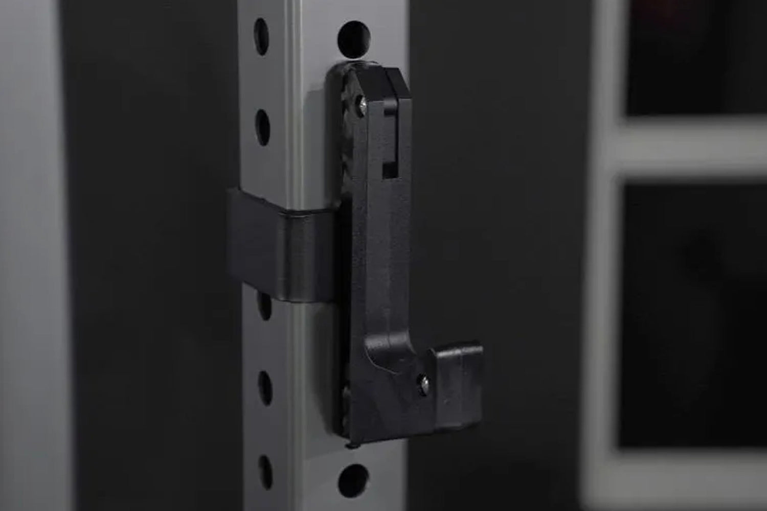 Black metal squat stand attachment mounted on vertical rail with adjustment holes, front angle view