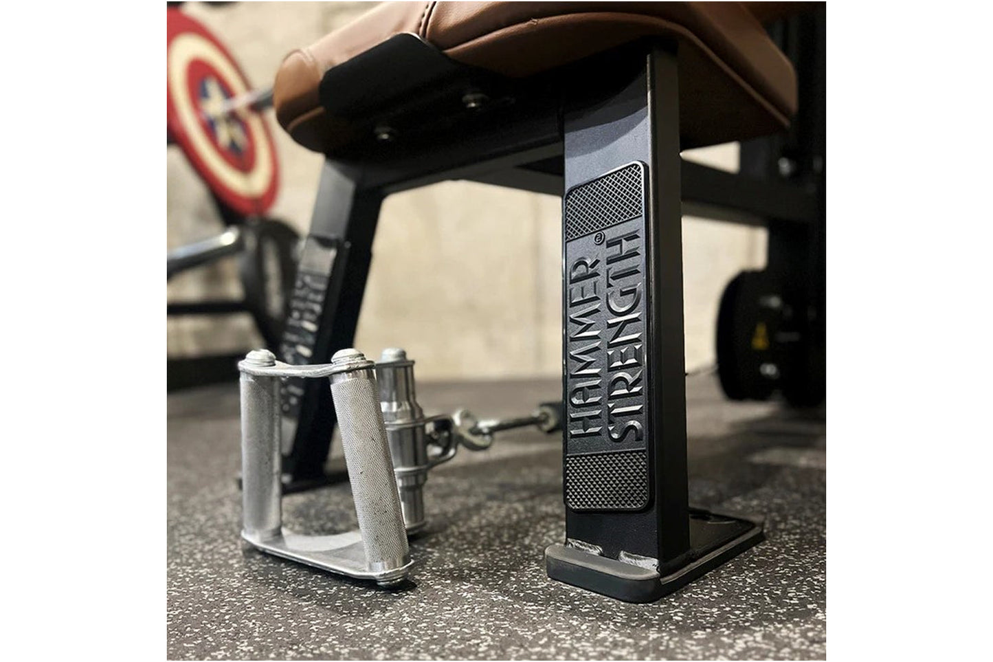 Black and silver Hammer Strength dual pulldown row machine with metal handles, shown on gym floor with blurred equipment in b