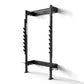Black metal squat rack with horizontal bar and tiered weight plate storage pegs on vertical uprights, mounted on white backgr
