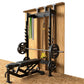Hammer Strength home squat rack with wood frame, black metal barbell, weight plates, and suspension straps on sand