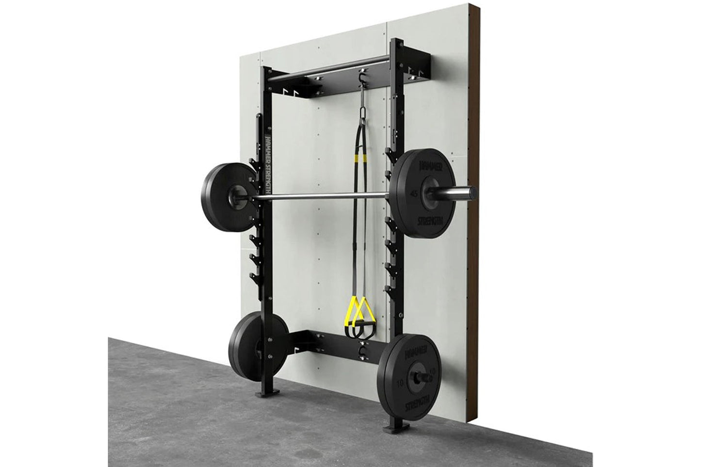 Wall-mounted squat rack with black metal frame, loaded barbell with weight plates, yellow suspension straps, and concrete flo