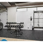 Black steel squat rack with weight plates and barbell in modern garage gym setting with rubber flooring