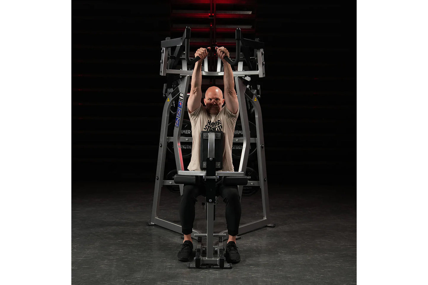 Hammer Strength Iso-Lateral High Row machine with model performing seated high row exercise, black and gray frame on dark bac