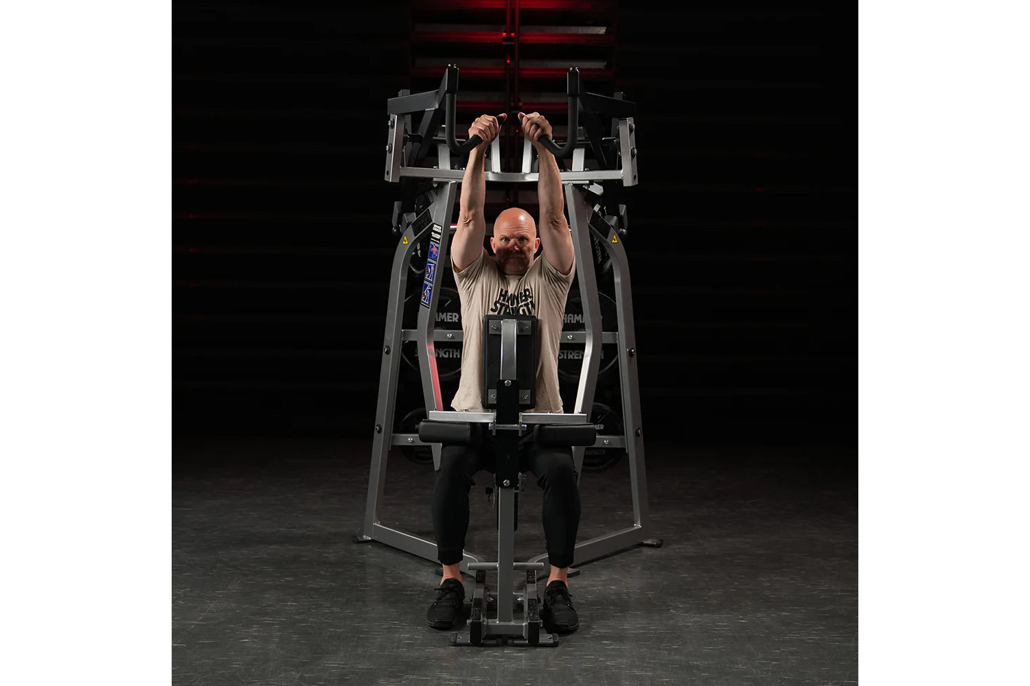 Hammer Strength Iso-Lateral High Row machine with model performing seated high row exercise, black and gray frame on dark bac