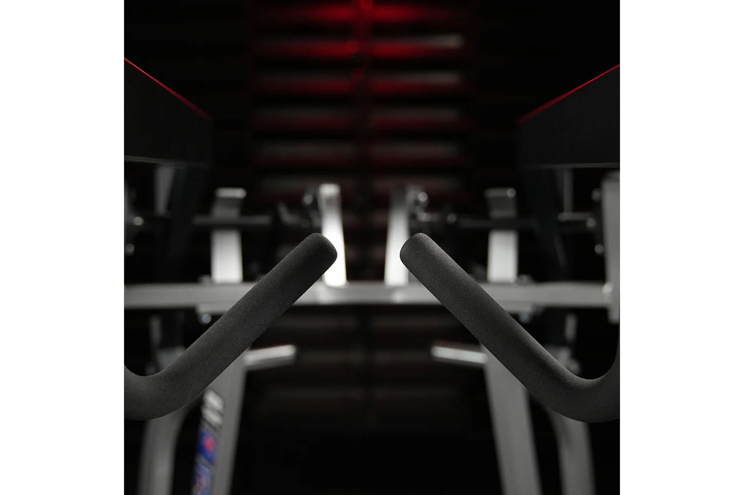 Black padded handles on Hammer Strength iso-lateral high row machine in gym setting with red accents