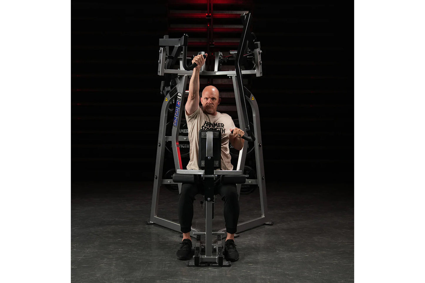 Hammer Strength Iso-Lateral High Row machine with male user demonstrating seated high row exercise on dark background