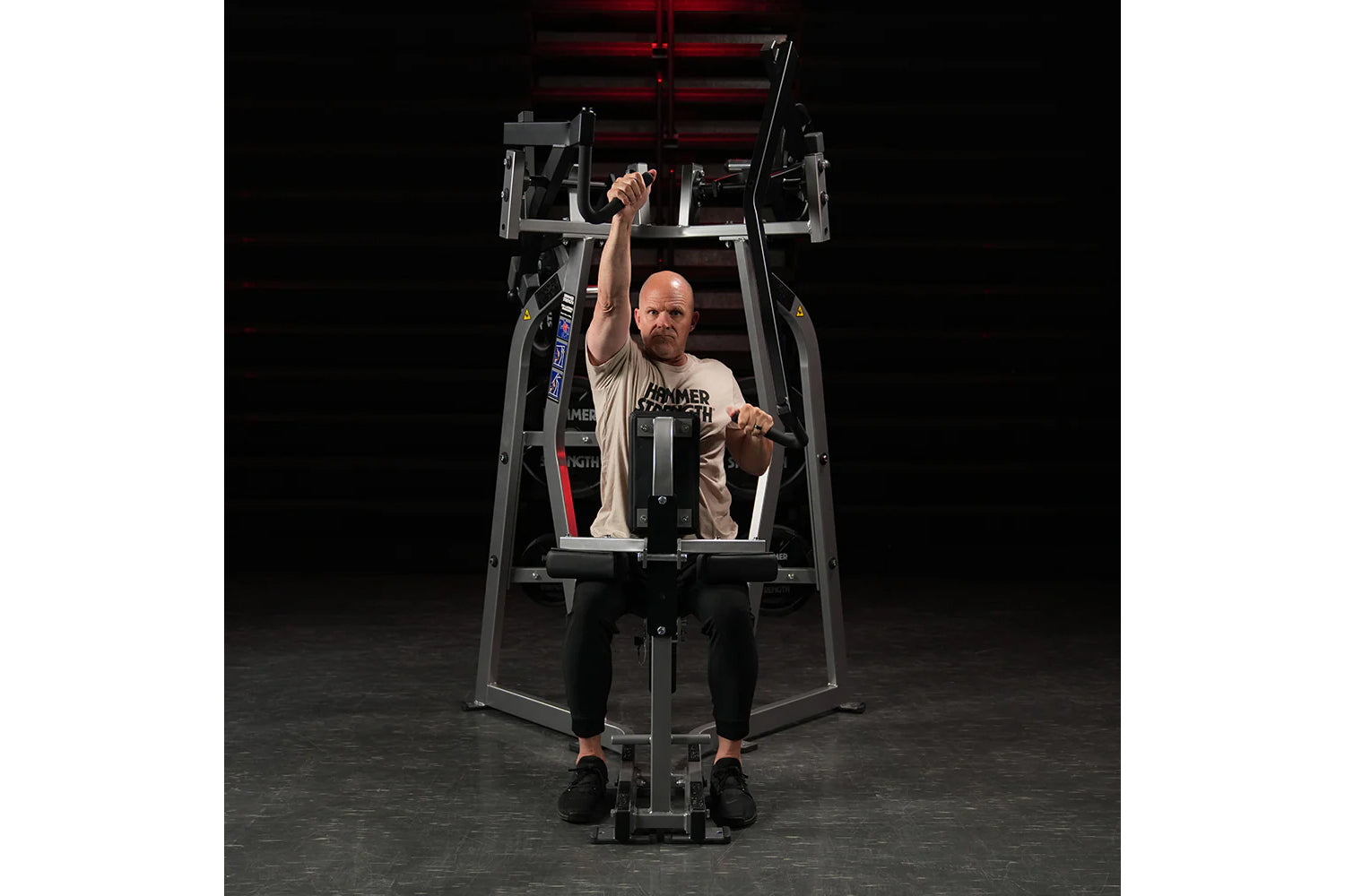 Hammer Strength Iso-Lateral High Row machine with male user demonstrating seated high row exercise on dark background