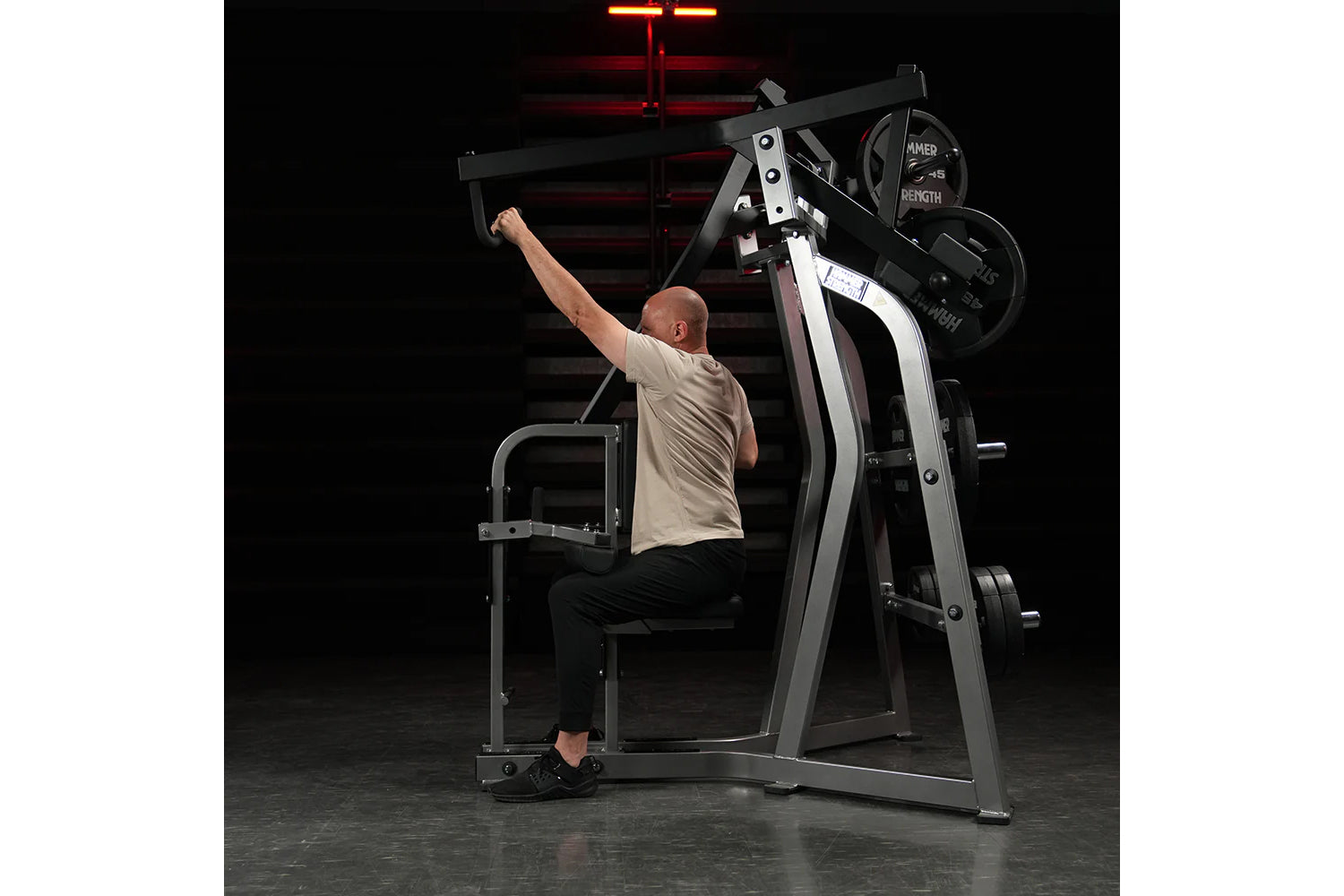 Man using black and silver Hammer Strength iso-lateral high row machine with weighted plates in gym setting